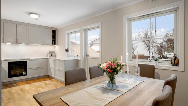 Kjøkkenet ligger naturlig tilbaketrukket fra stuen og er innredet med lyse slette flater og benkeplate av stein.