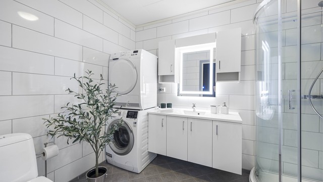 Badet er romslig og utstyrt med servantinnredning, dusjkabinett, toalett og opplegg for vaskemaskin.