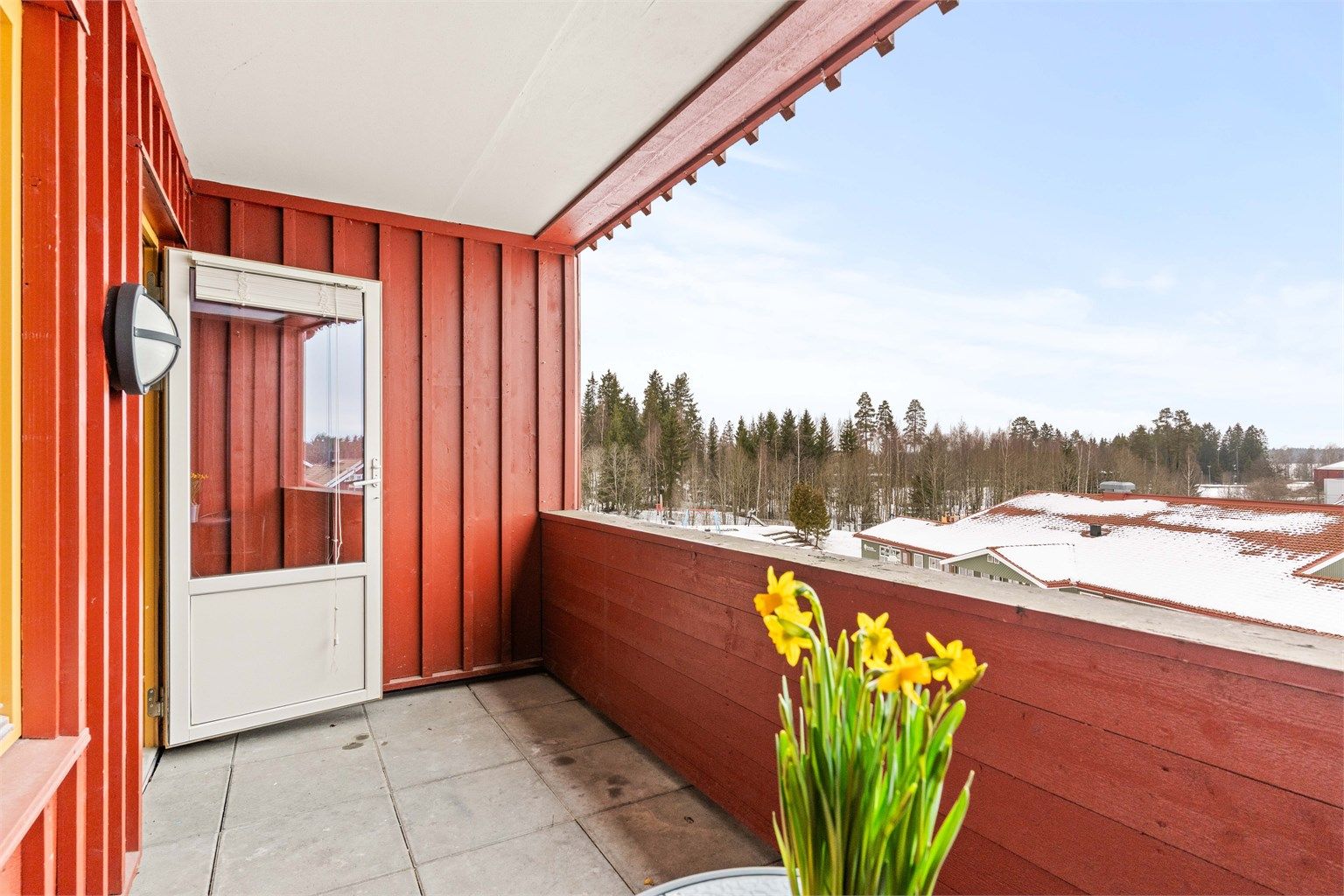 Balkongen har betongheller på gulvet, rekkverk av tre, samt utelys og stikkontakt.