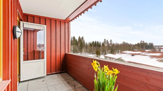 Balkongen har betongheller på gulvet, rekkverk av tre, samt utelys og stikkontakt.