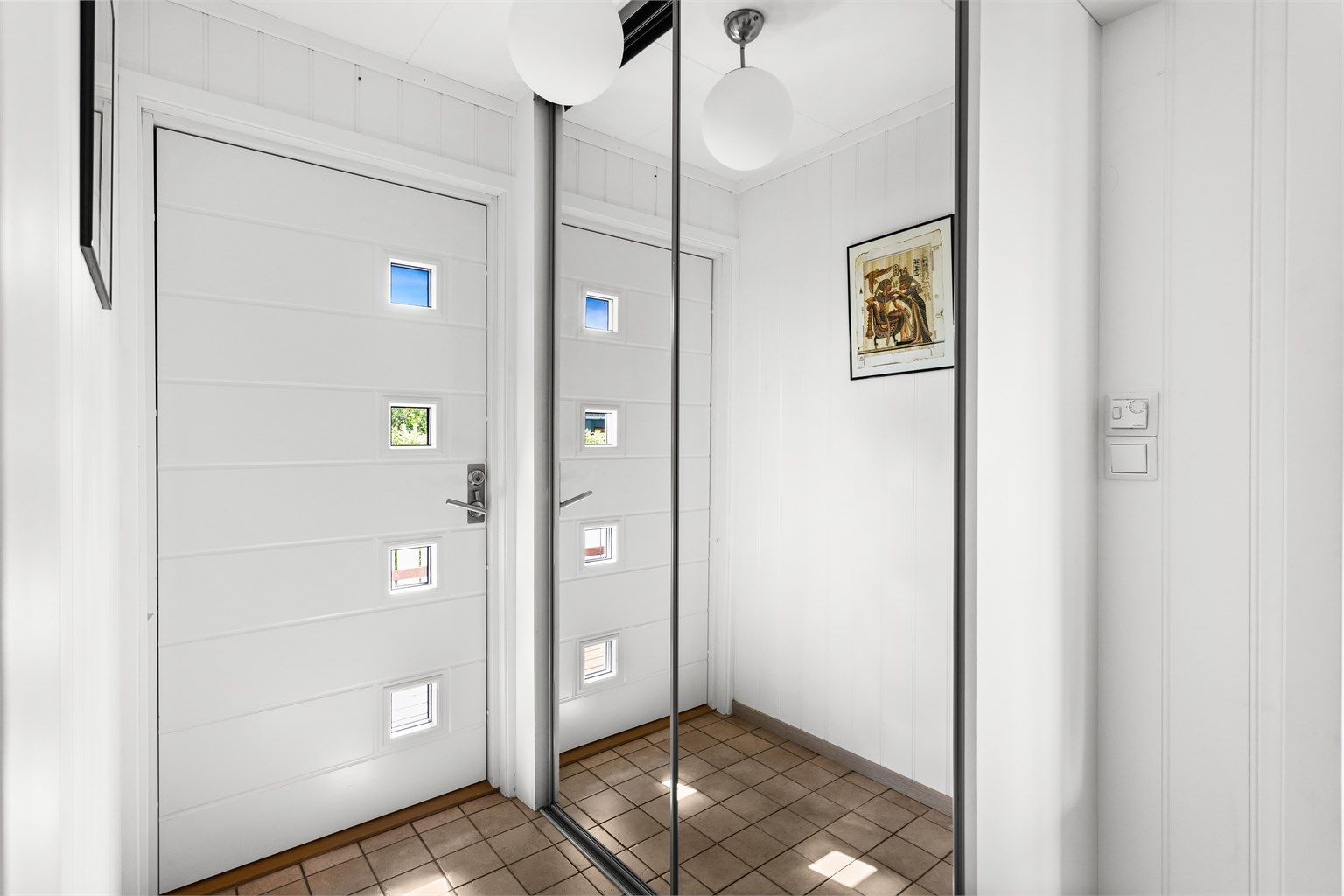 Den romslige entréen gir både funksjonalitet og et stilrent uttrykk med skyvedører som gir enkel oppbevaring av yttertøy.  