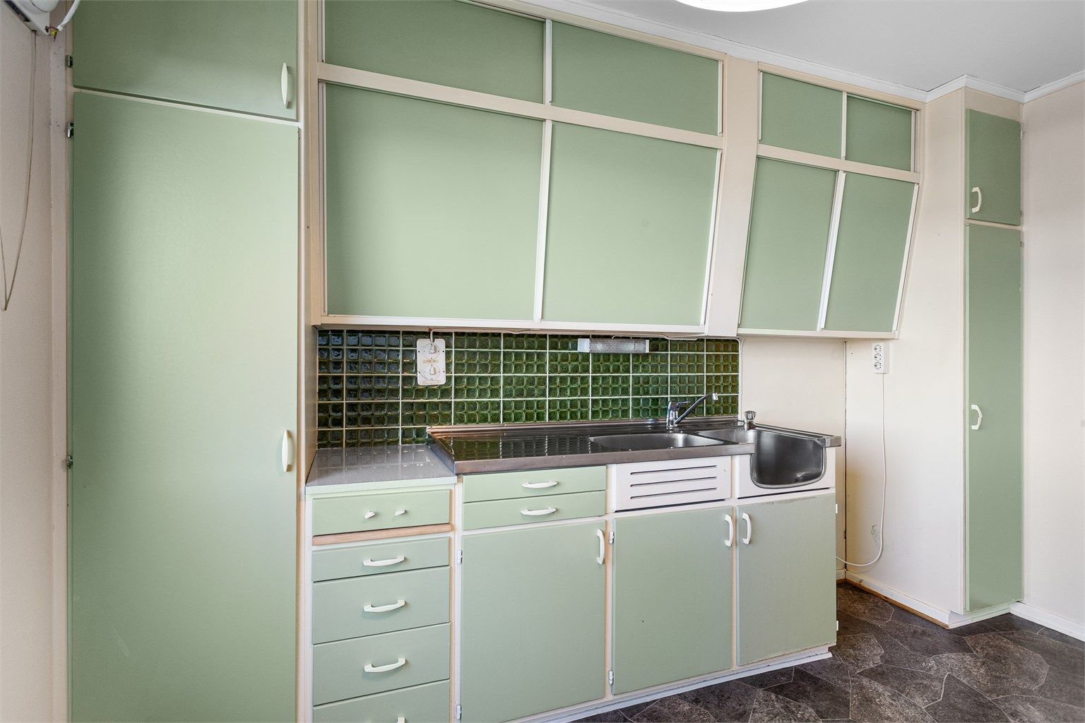 Kjøkkenet har en original innredning fra byggeåret med slette fronter og god skapplass.