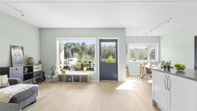 Romslig stue med store vinduer og utgang til uteplass.