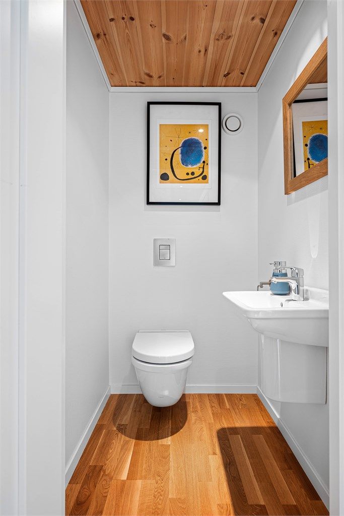
Wc i denne etasjen har parkett på gulv, lyse vegger, enkel servant.