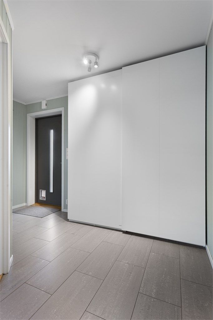 Entré med flislagt gulv med varme. Praktisk oppbevaringsplass i skyvedørsgarderobe.