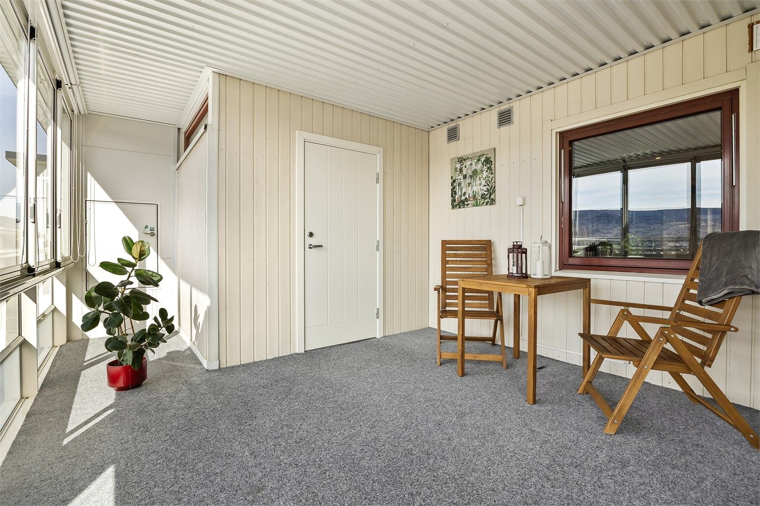Balkongen har skyvbare glassfelt, innvendig solskjerming (lameller og rullgardin) og teppebelagt gulv.