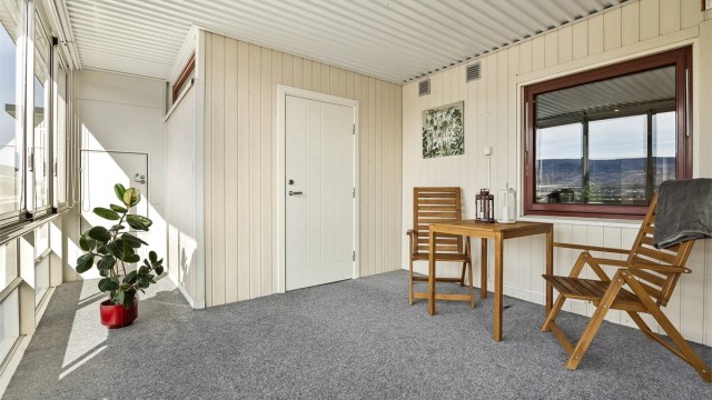 Balkongen har skyvbare glassfelt, innvendig solskjerming (lameller og rullgardin) og teppebelagt gulv.