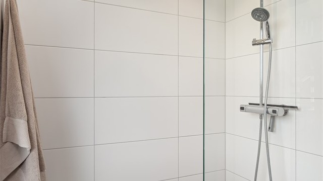 Badet er innredet med gulvstående toalett, servantmøblement og dusjhjørne
