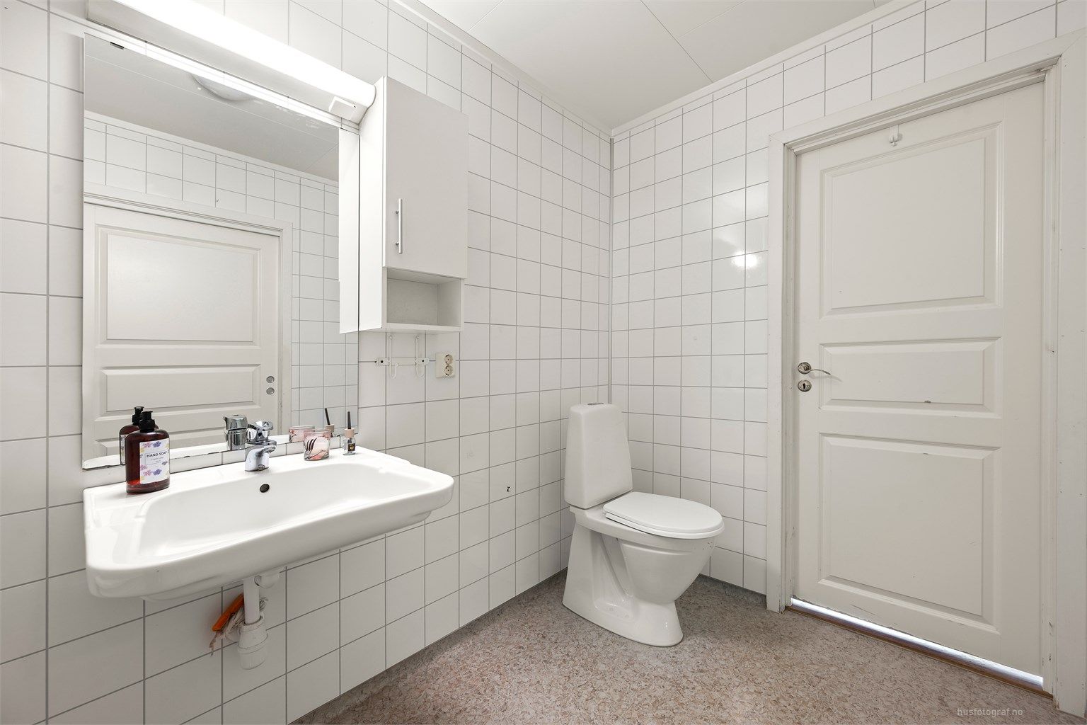 Badet er innredet med gulvstående toalett, vegghengt servant og badekar 