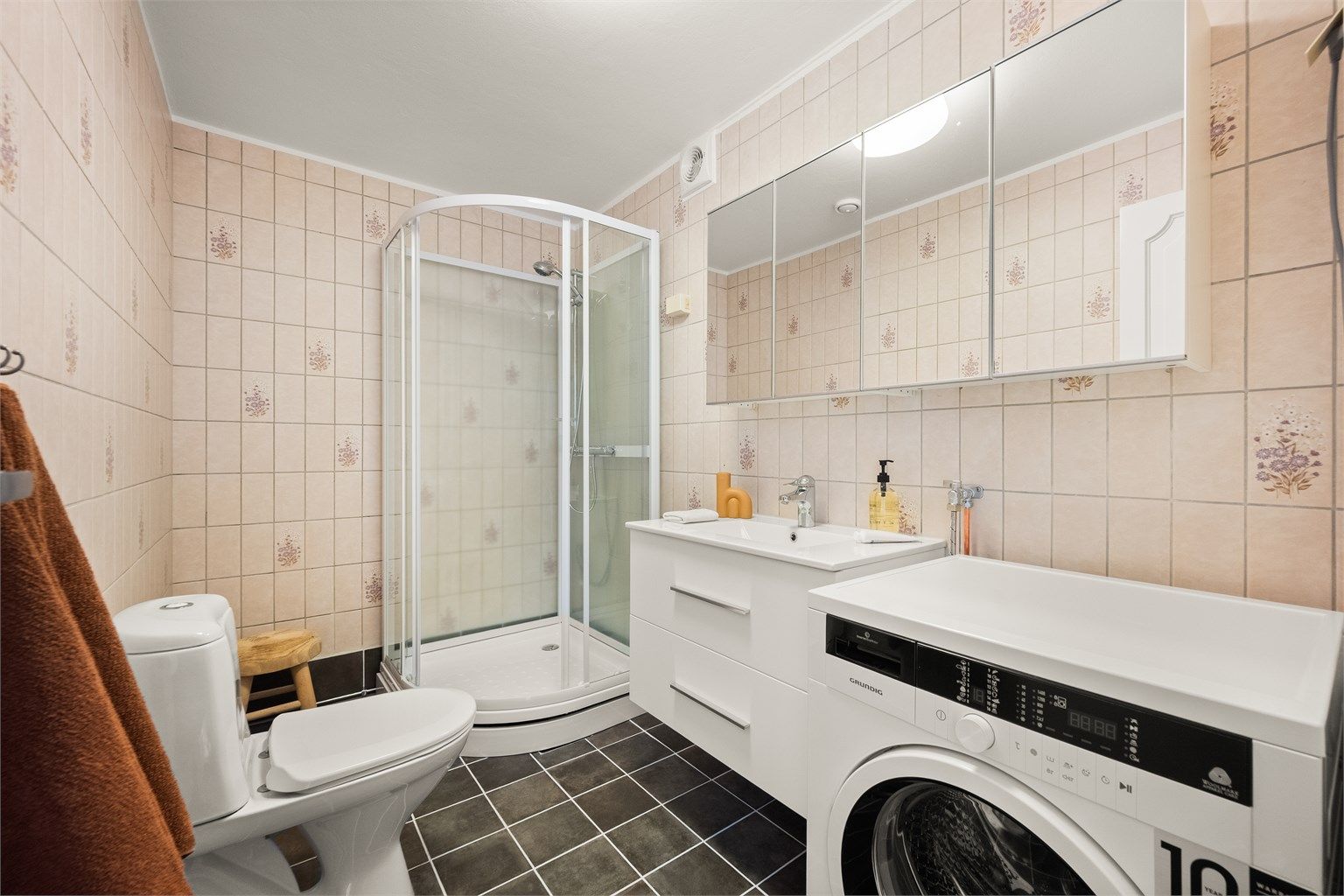 Badet i den minste delen/leilighten er flislagt, har gulvvarme, dusjkabinett og opplegg for vaskemaskin.