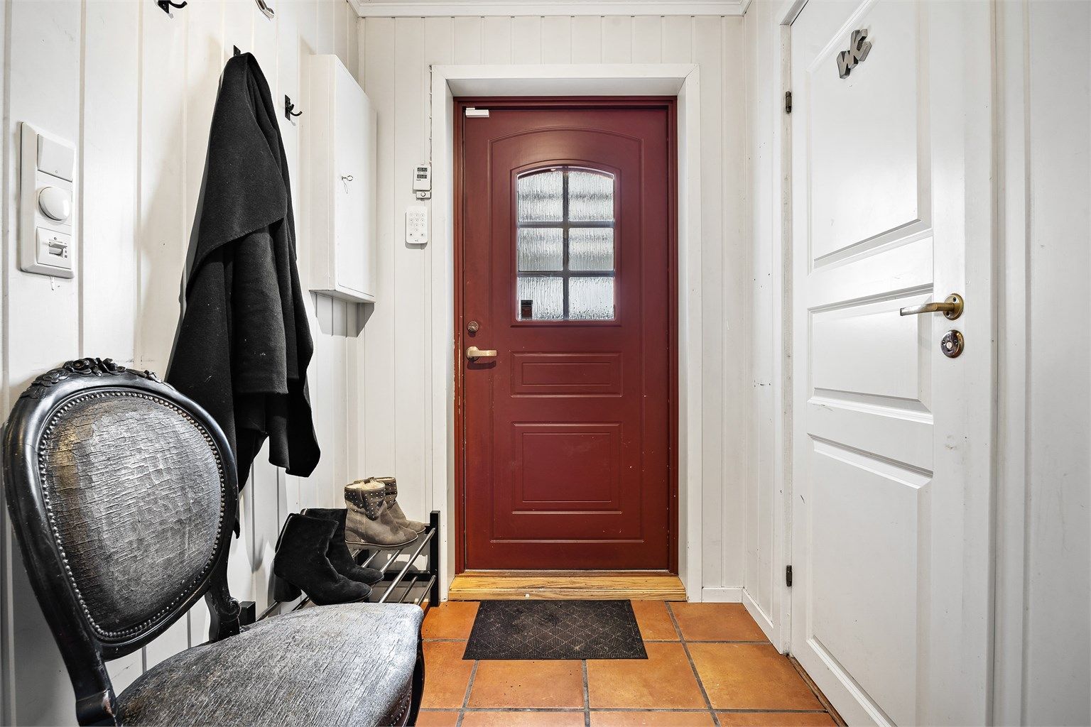 Romslig entré med flislagt gulv - Del av rommet er ikke byggemeldt, tidligere utvendig areal.