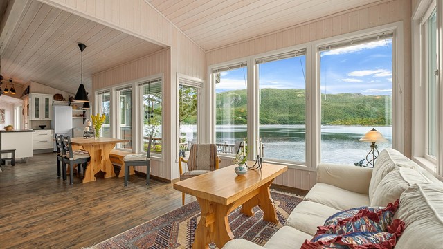 Stuen har en åpen og luftig forbindelse mot spiseplass og kjøkken – med sjøen som gjennomgående utsikt.