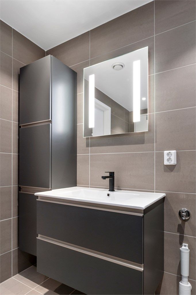 Badet er utstyrt med lekker innredning med mørke glatte fronter.