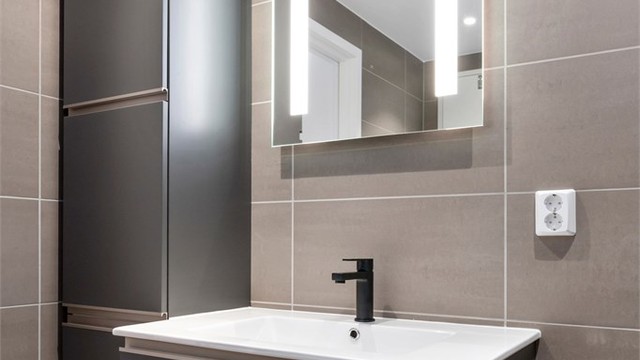 Badet er utstyrt med lekker innredning med mørke glatte fronter.