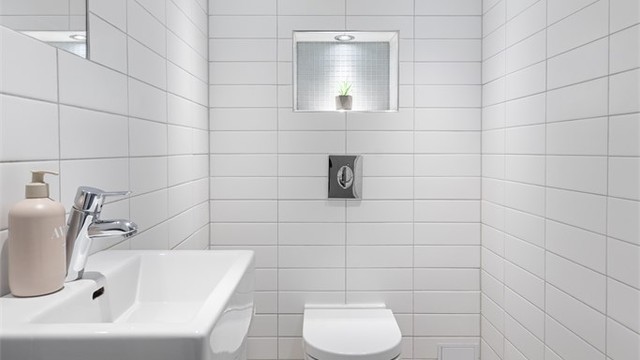 Toalettrom i kjelleren med flislagte overflater, gulvvarme og veggmontert toalett.
