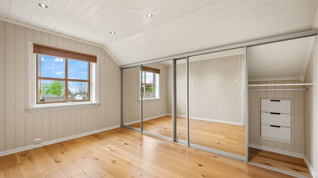 Romslig soverom med god plass og en stor skyvedørsgarderobe for effektiv oppbevaring.