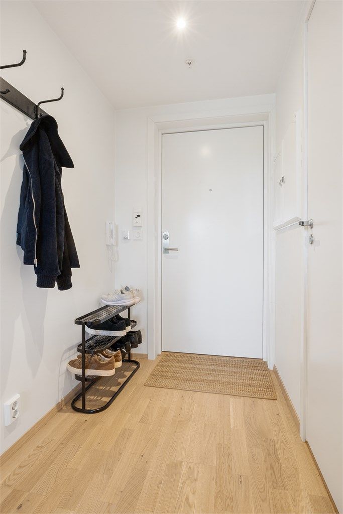 Entré med lysmalte flater og plass til klesoppheng og skohylle ved inngangsdøren.