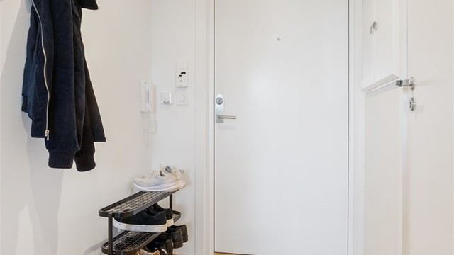 Entré med lysmalte flater og plass til klesoppheng og skohylle ved inngangsdøren.