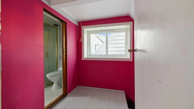 Gang i andre etasje med malt tregulv og skyvedør inn til badet.