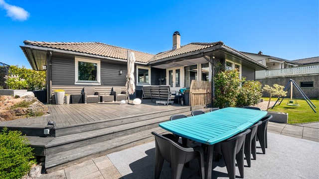 Tomten er opparbeidet med terrasse, belegningsstein, heller, plenarealer og variert beplantning.