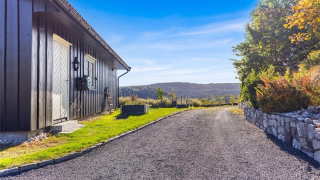 Gruset innkjørsel rammet inn av forstøtningsmur i naturstein og grøntarealer.
