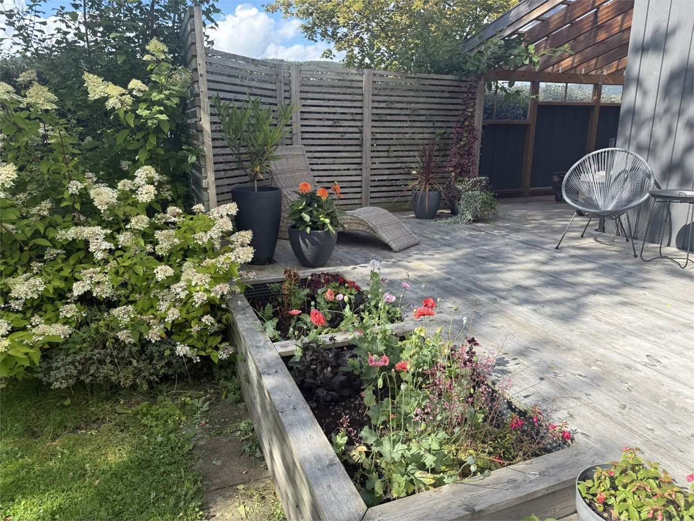 Markterrassen omkranset av frodig sommerbeplantning.