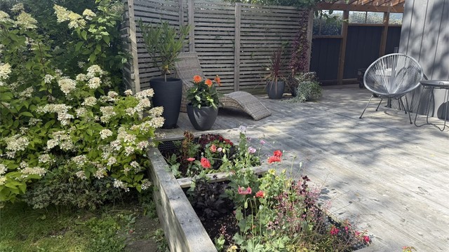 Markterrassen omkranset av frodig sommerbeplantning.