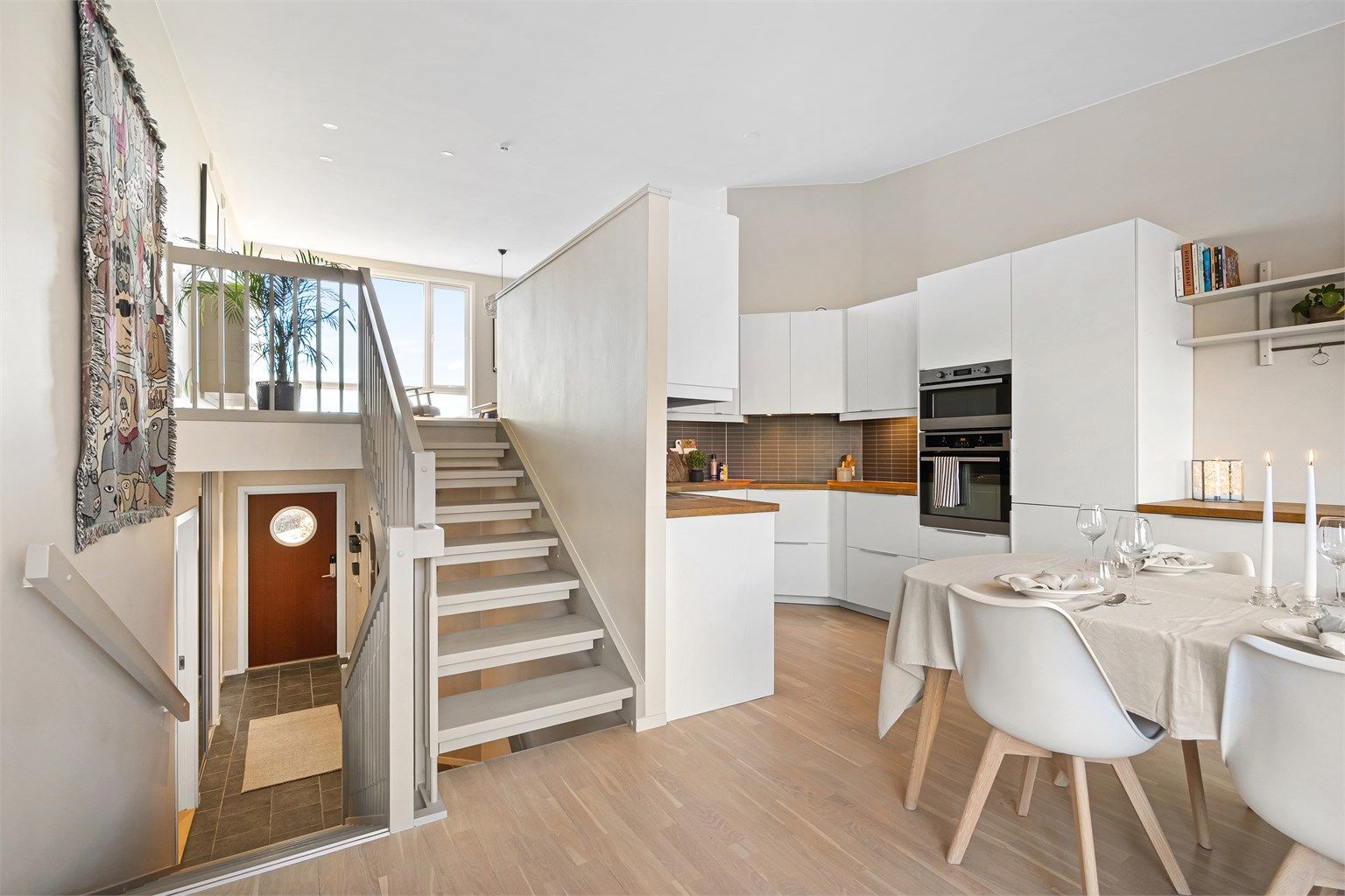 Tidløst, hvitt kjøkken med slette fronter, rikelig med skap og benkeplass.