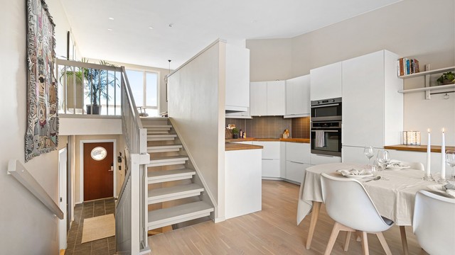 Tidløst, hvitt kjøkken med slette fronter, rikelig med skap og benkeplass.