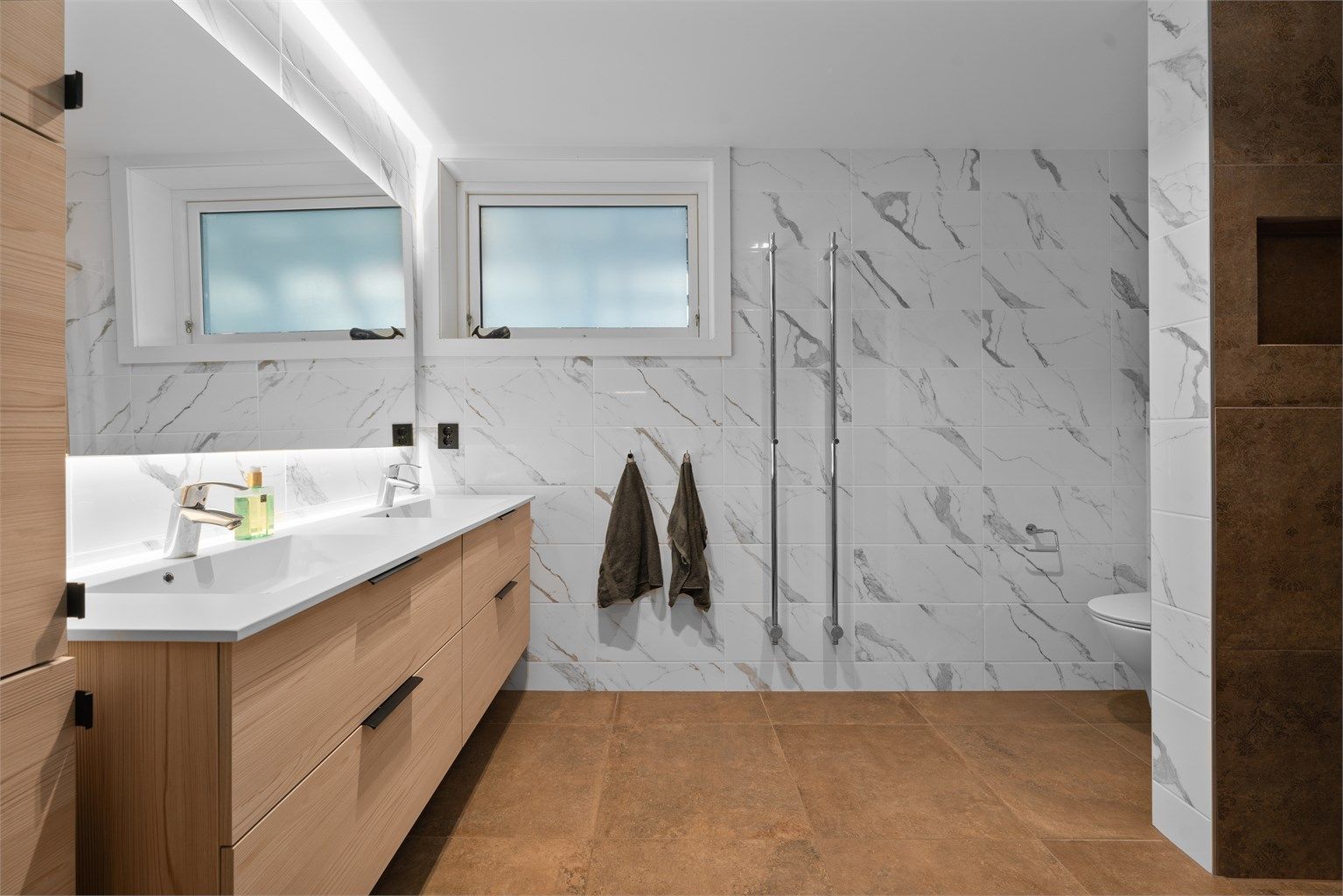 Bad i underetasje. Romslig og pent bad med varmekabler i gulv. Praktiske håndklevarmere montert på vegg.