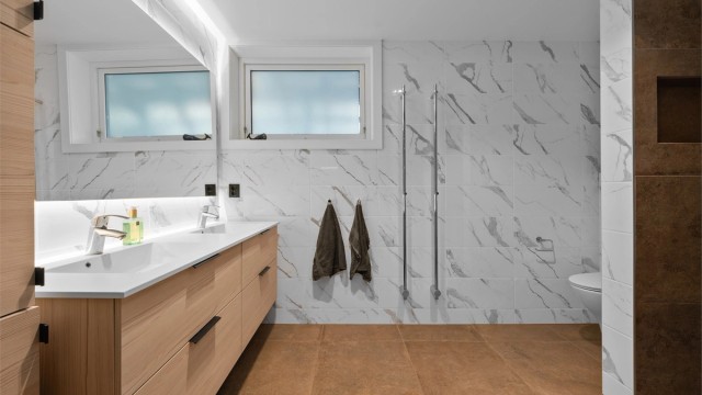 Bad i underetasje. Romslig og pent bad med varmekabler i gulv. Praktiske håndklevarmere montert på vegg.