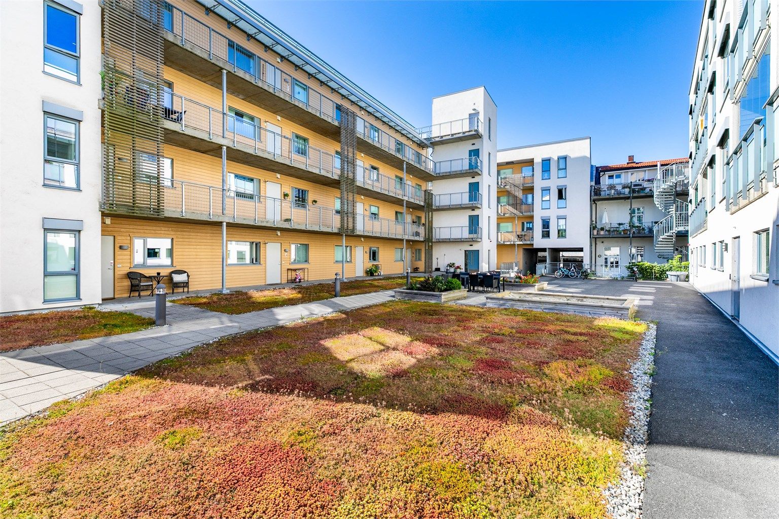 Sameiets skjermede gårdsrom er pent opparbeidet og inkluderer sandkasse samt sittegrupper for beboerne.