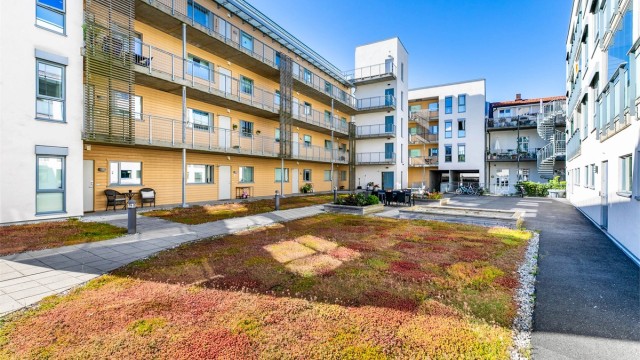 Sameiets skjermede gårdsrom er pent opparbeidet og inkluderer sandkasse samt sittegrupper for beboerne.