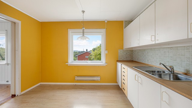 Kjøkkenet har laminatgulv og plass til spisebord ved vinduet.
