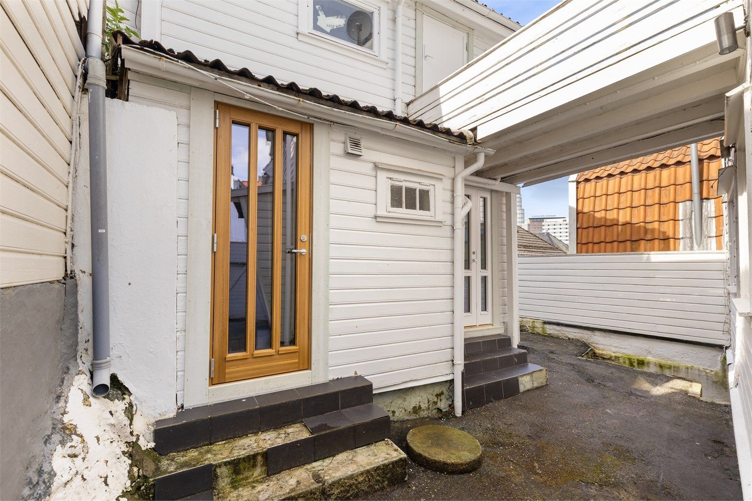 Uteområdet mellom hovedhuset og annekset, med adkomst til flere av enhetene.