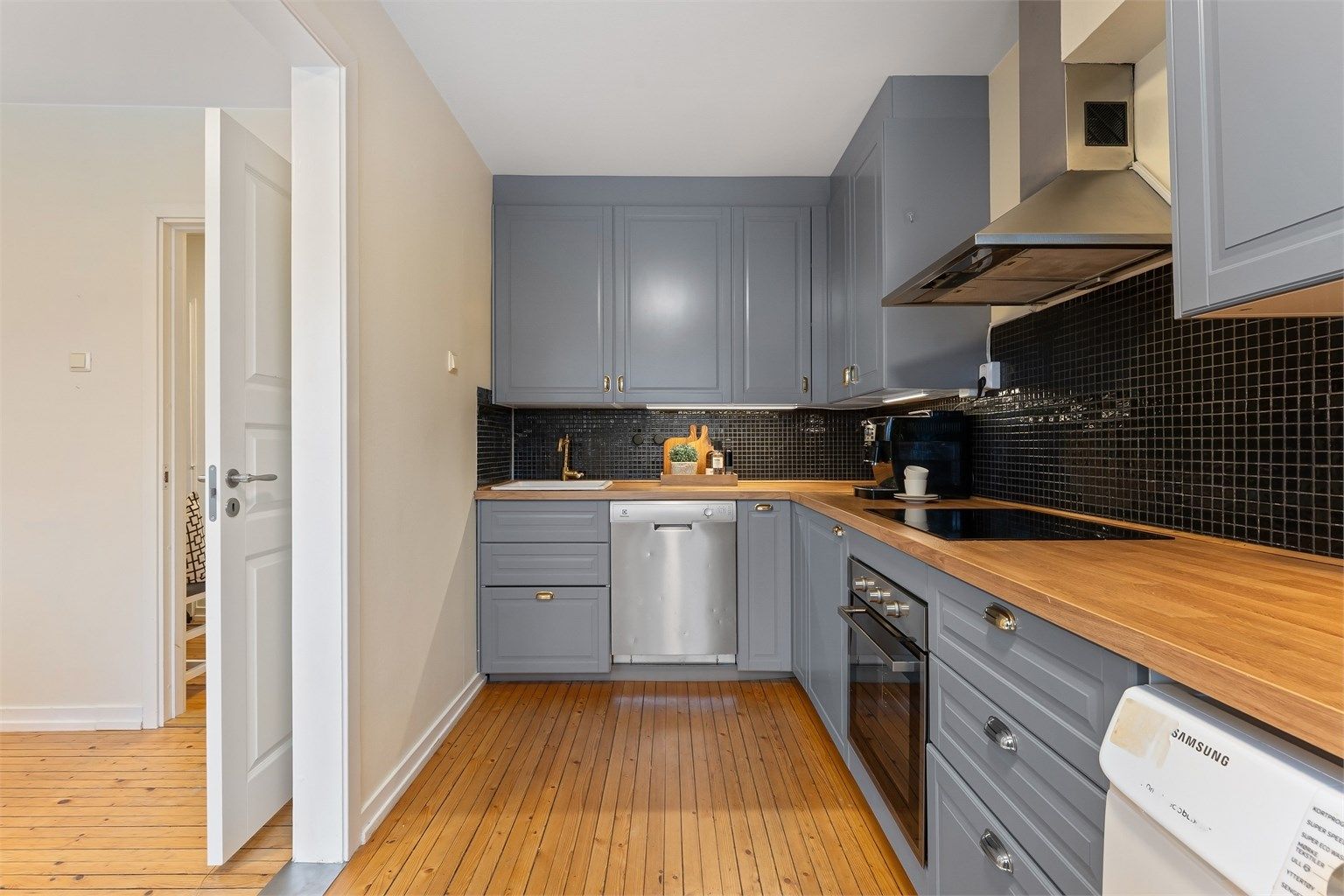 Kjøkkeninnredningen har laminatbenkeplate og fliser mellom benk og overskap.