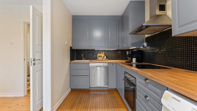 Kjøkkeninnredningen har laminatbenkeplate og fliser mellom benk og overskap.