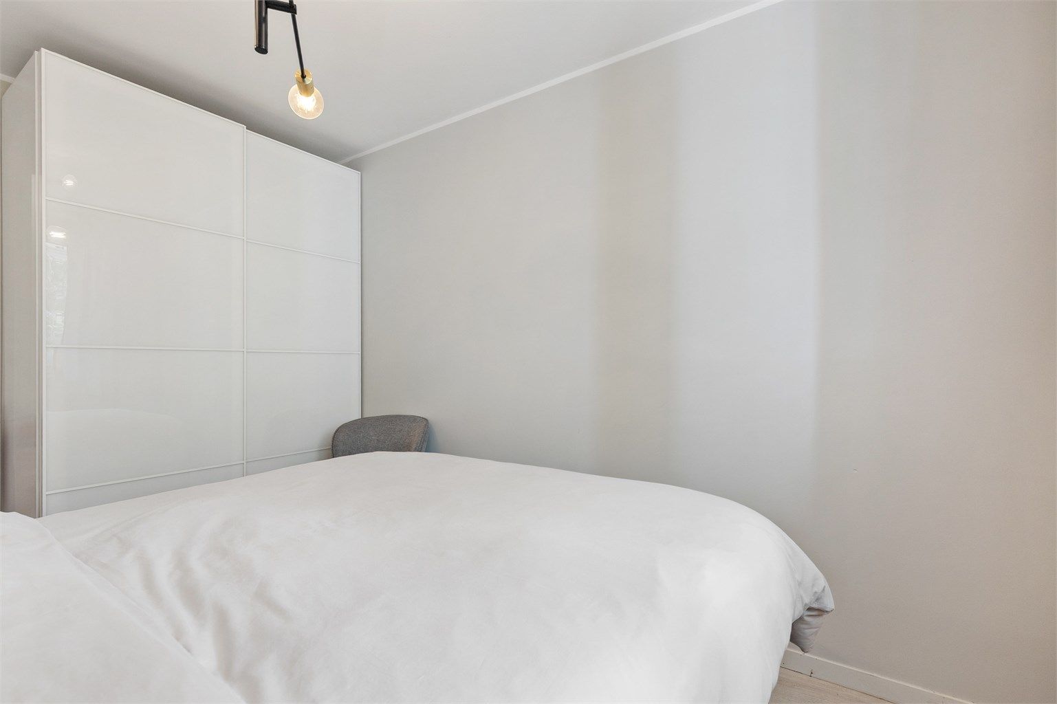 Skyvedørsgarderobe med glatte, hvite fronter gir rikelig med oppbevaringsplass.