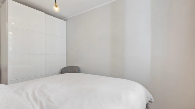 Skyvedørsgarderobe med glatte, hvite fronter gir rikelig med oppbevaringsplass.