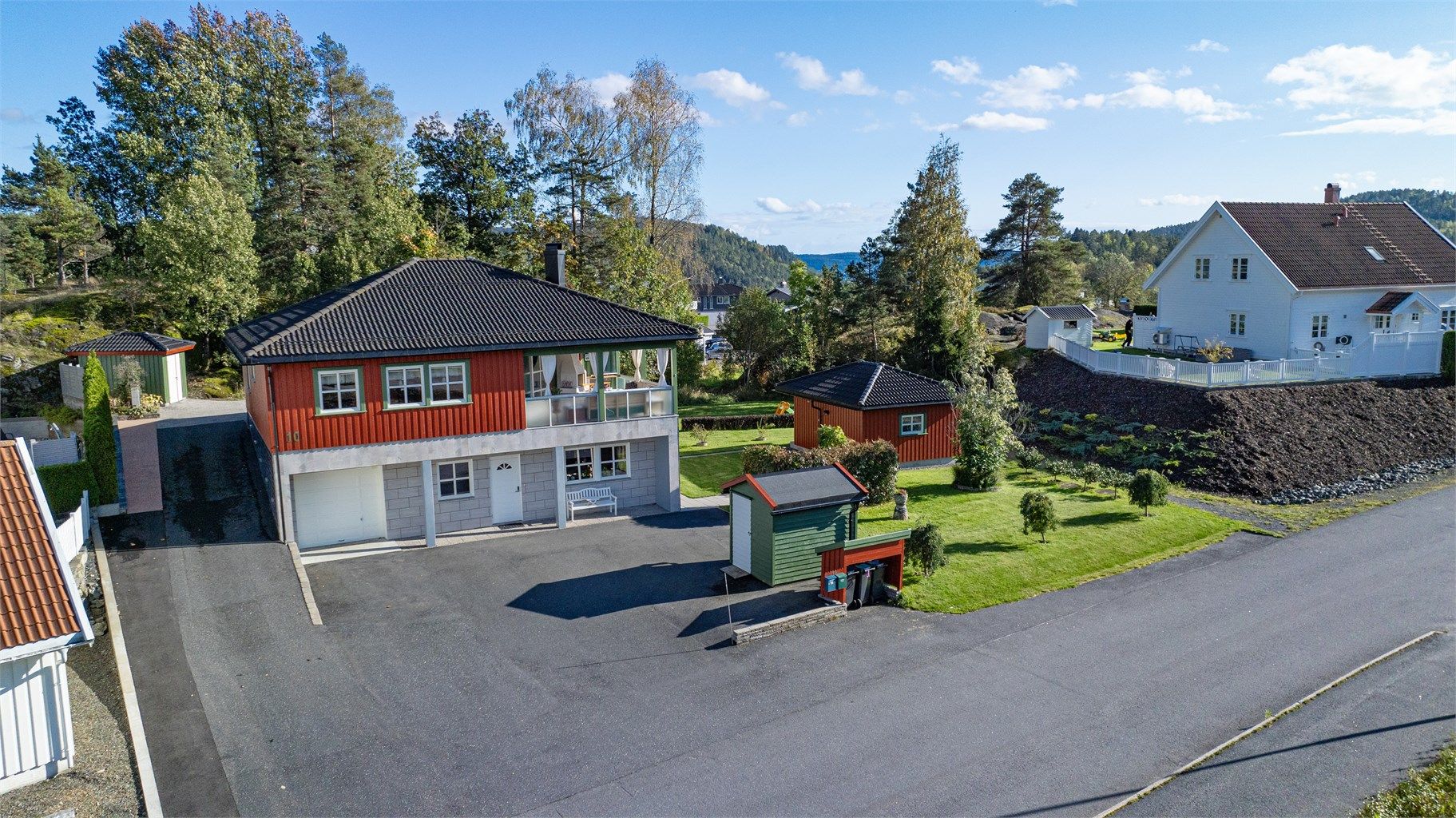 Tomten er pent opparbeidet og beplantet, asfaltert gårdsplass.