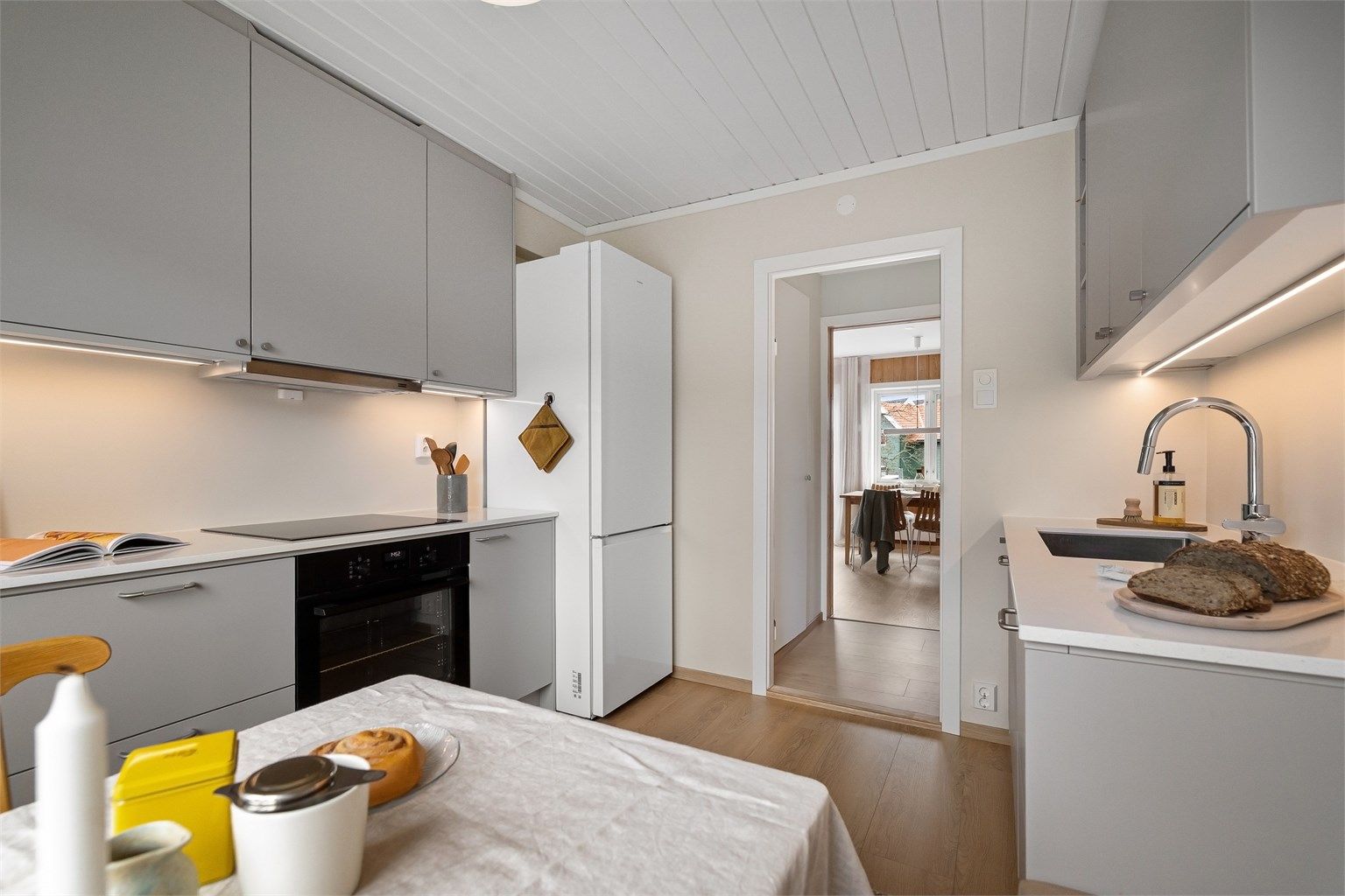 Glatte fronter i lys grå utførelse, benkeplate i stein og underlimt, rustfri oppvaskkum med ett-greps armatur