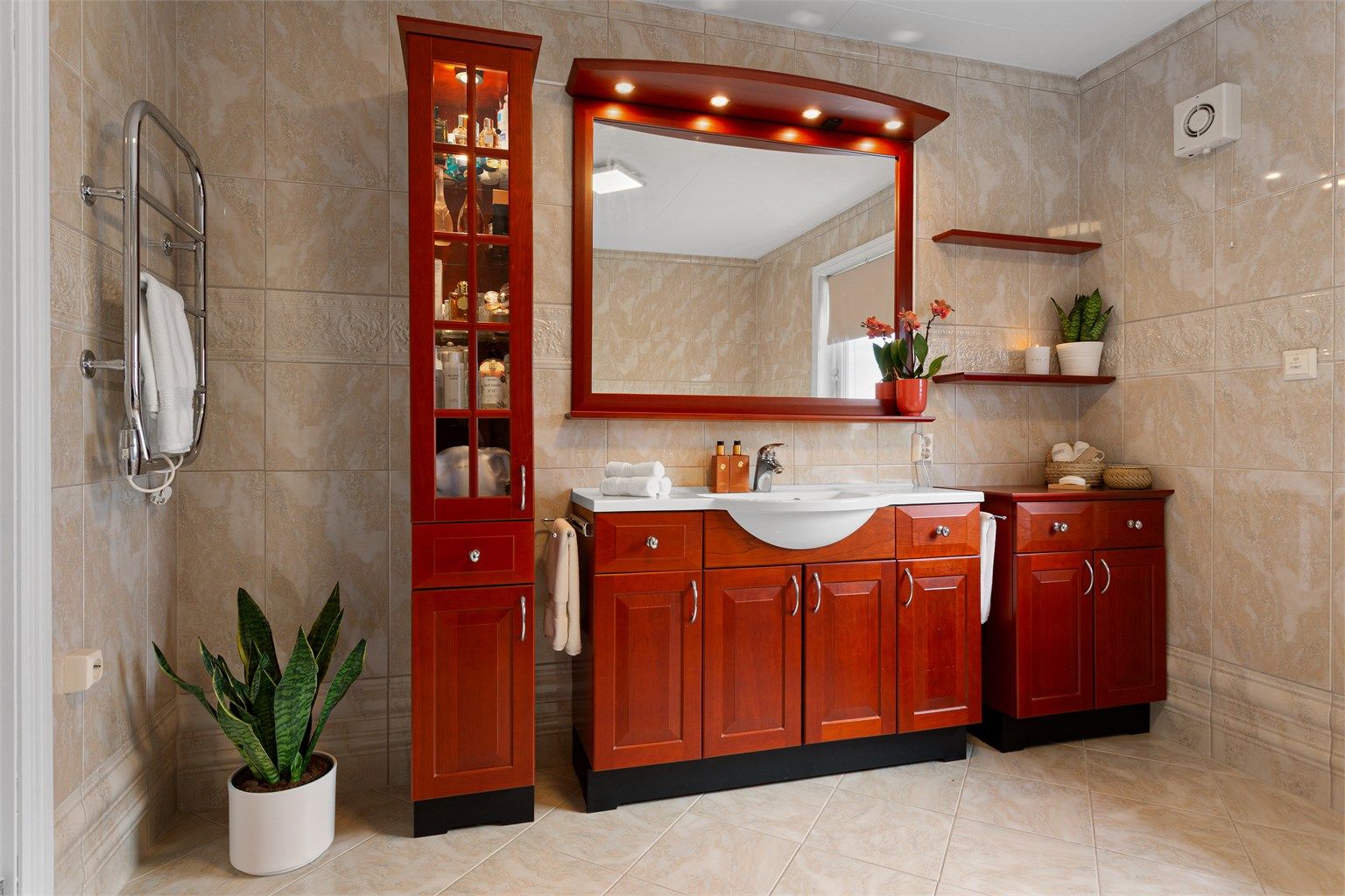 Stort flislagt bad med gulvvarme.  Innredet med gulvstående servantskap med profilerte fronter og ovenpåliggende servant.