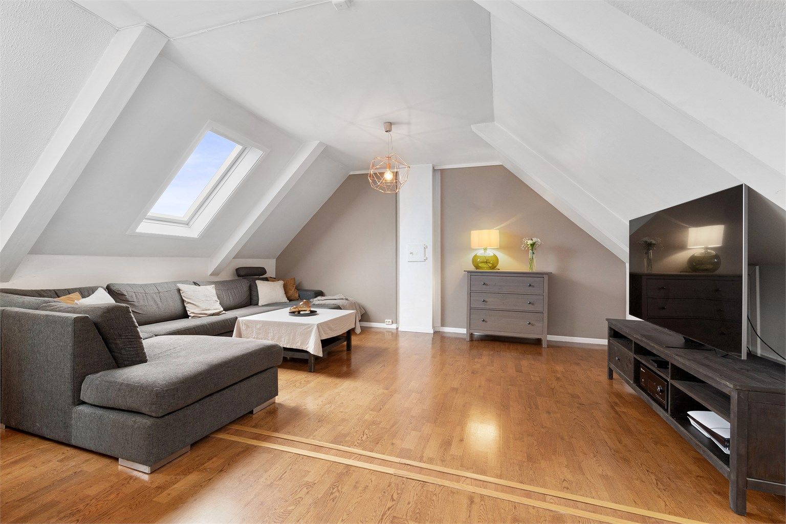 Leiligheten har skråtak og takvinduer noe som gir en særpreg -  her fra sofakroken på stuen