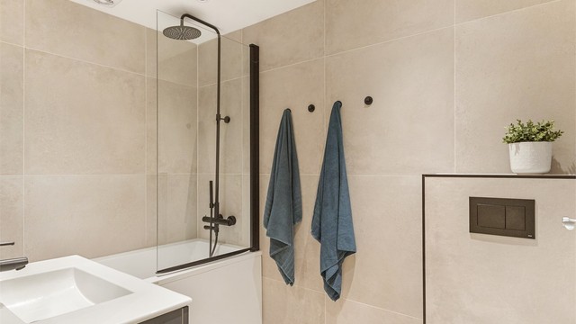 Lyst og innbydende baderom fra 2020, med gulvvarme og badekar med svingbare glassdører.
