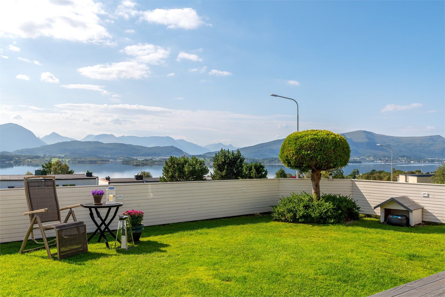 Tomten er inngjerdet med tregjerde og pent opparbeidet med plen i forkant av terrassen