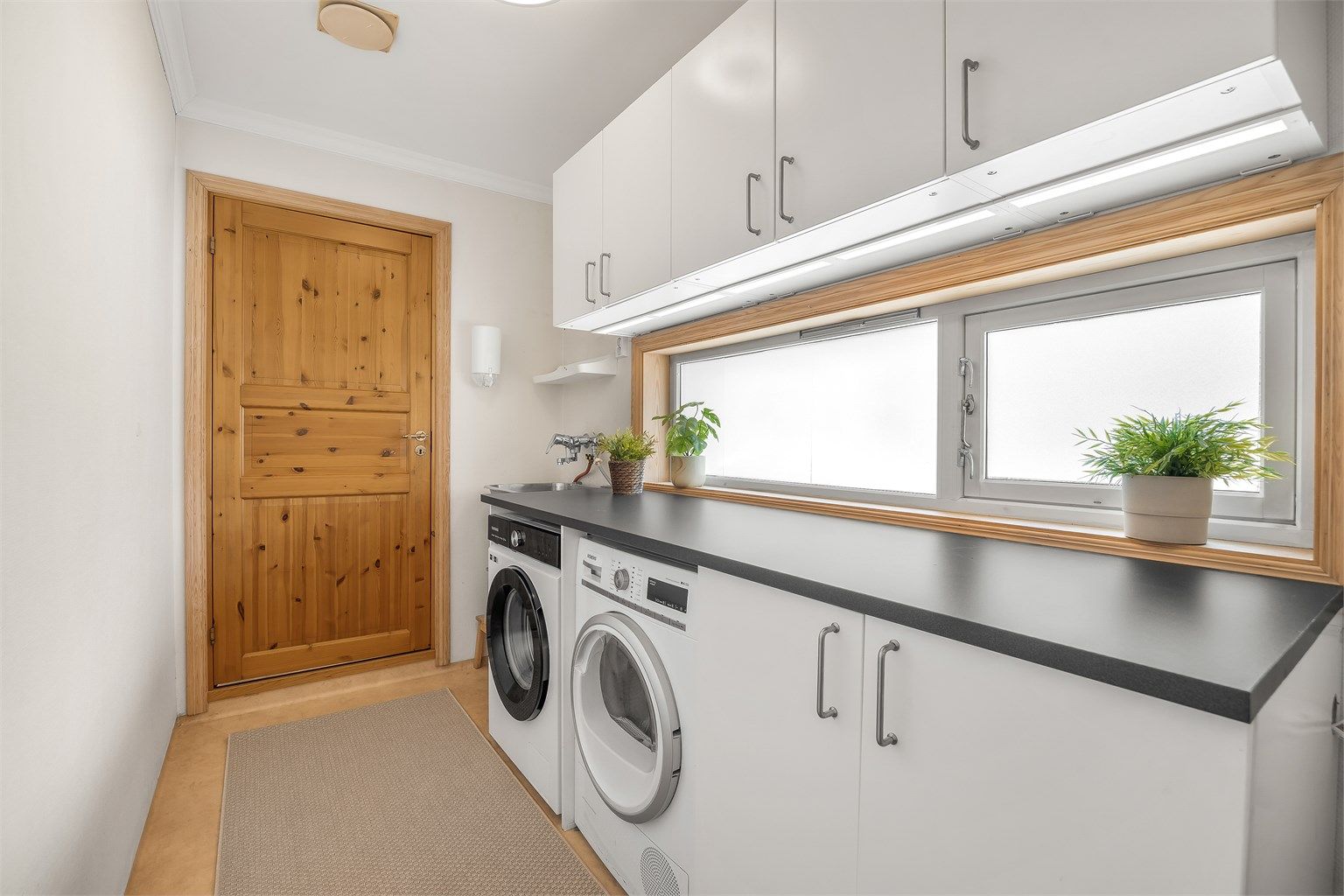 Separat vaskerom i første etasje med skapinnredning, utslagsvask og opplegg for vaskemaskin/tørketrommel.