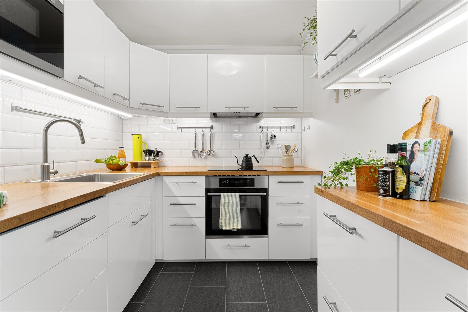 Kjøkkeninnredning fra 2015 med høyglansfronter, benkeplater i heltre og integrerte hvitevarer.