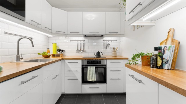 Kjøkkeninnredning fra 2015 med høyglansfronter, benkeplater i heltre og integrerte hvitevarer.