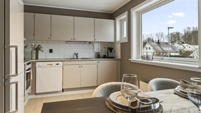 Smakfullt kjøkken med malte fronter og flis over benkeplaten