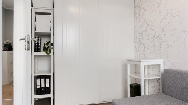 Rommet har en dekorativ tapetvegg, skyvedørsgarderobe og parkett på gulv.